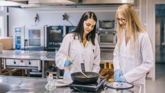 A photograph of two female scientists cooking meet in a laboratory