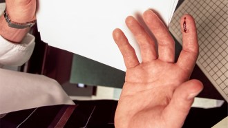 A photo of a hand with a paper cut on the index finger.