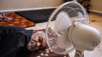 A man sleeps next to an electric fan during a heat wave in Syria in July 2023.